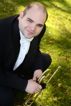 Photo of Mark D'Angelo with his trumpet with field of green grass in the background